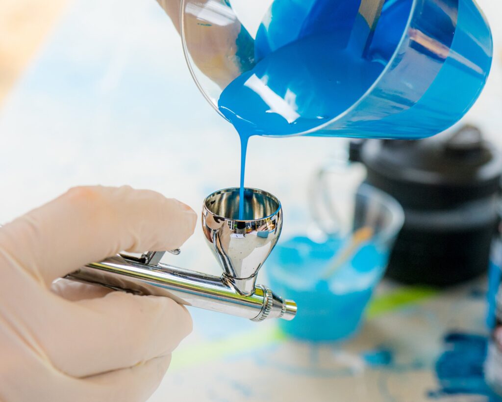 blue paint being poured into a dual action airbrush