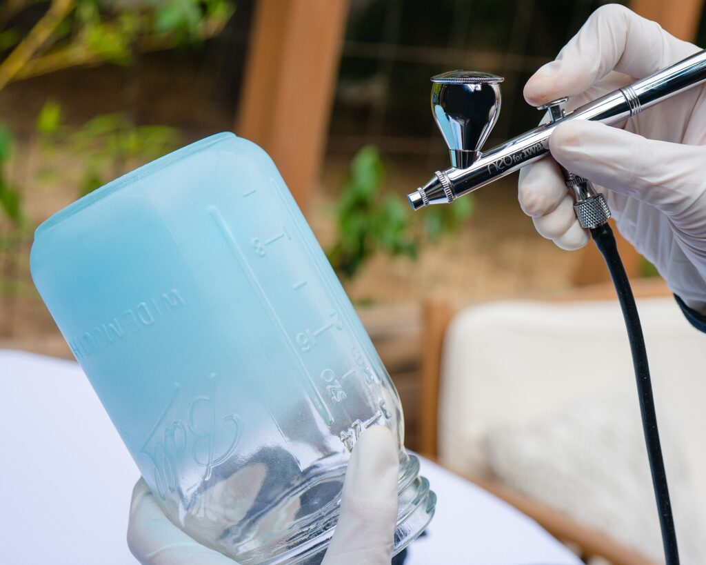 dual action airbrush spraying blue on mason jar