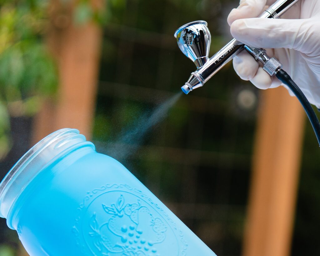 iwata dual action airbrush spraying blue createx on mason jar