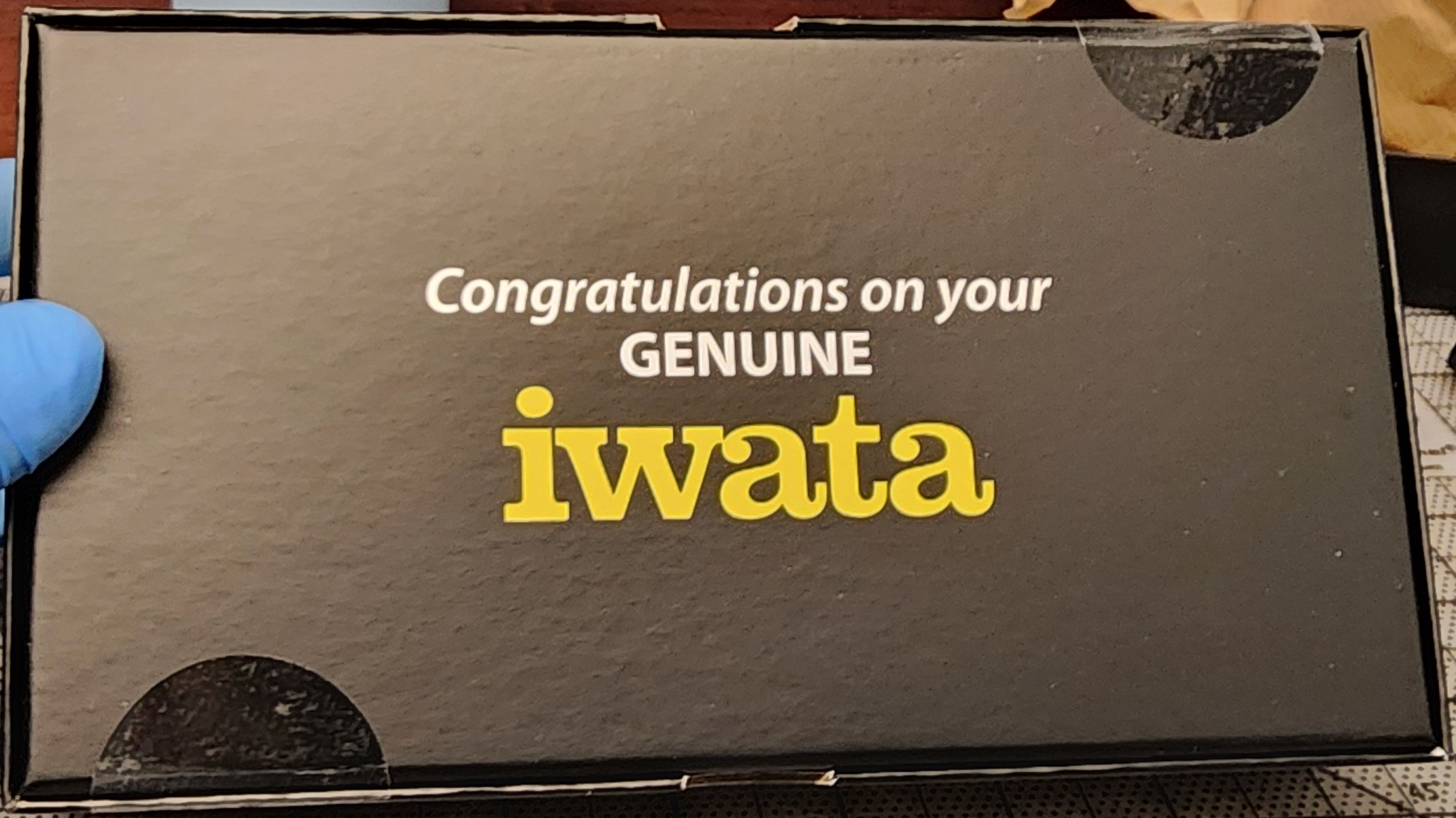 Bottom of the black eclipse cs box showing 2 1.5 inch clear circle seals applied to the lower spine near the left edge and the upper spine near the right edge, when the iwata logo is positioned correctly