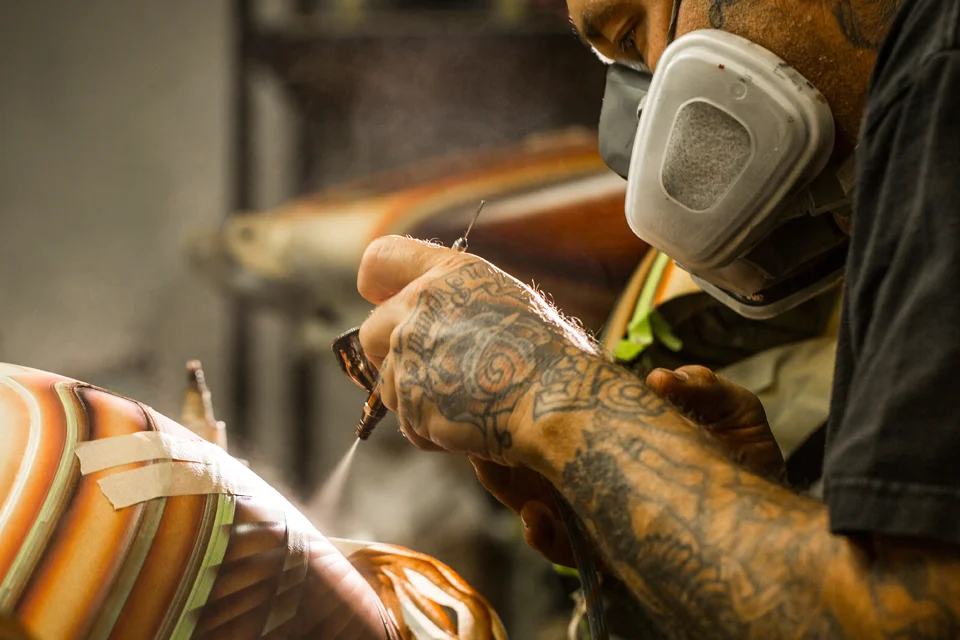 A custom automotive painter airbrushing lowrider style graphics on a motorcycle tank